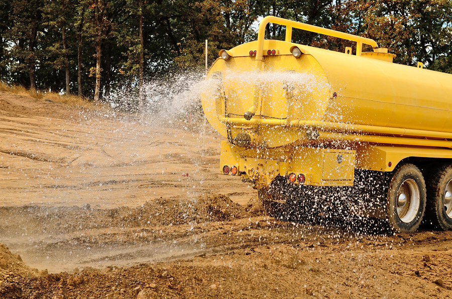 Water truck spraying water onto prepared material.